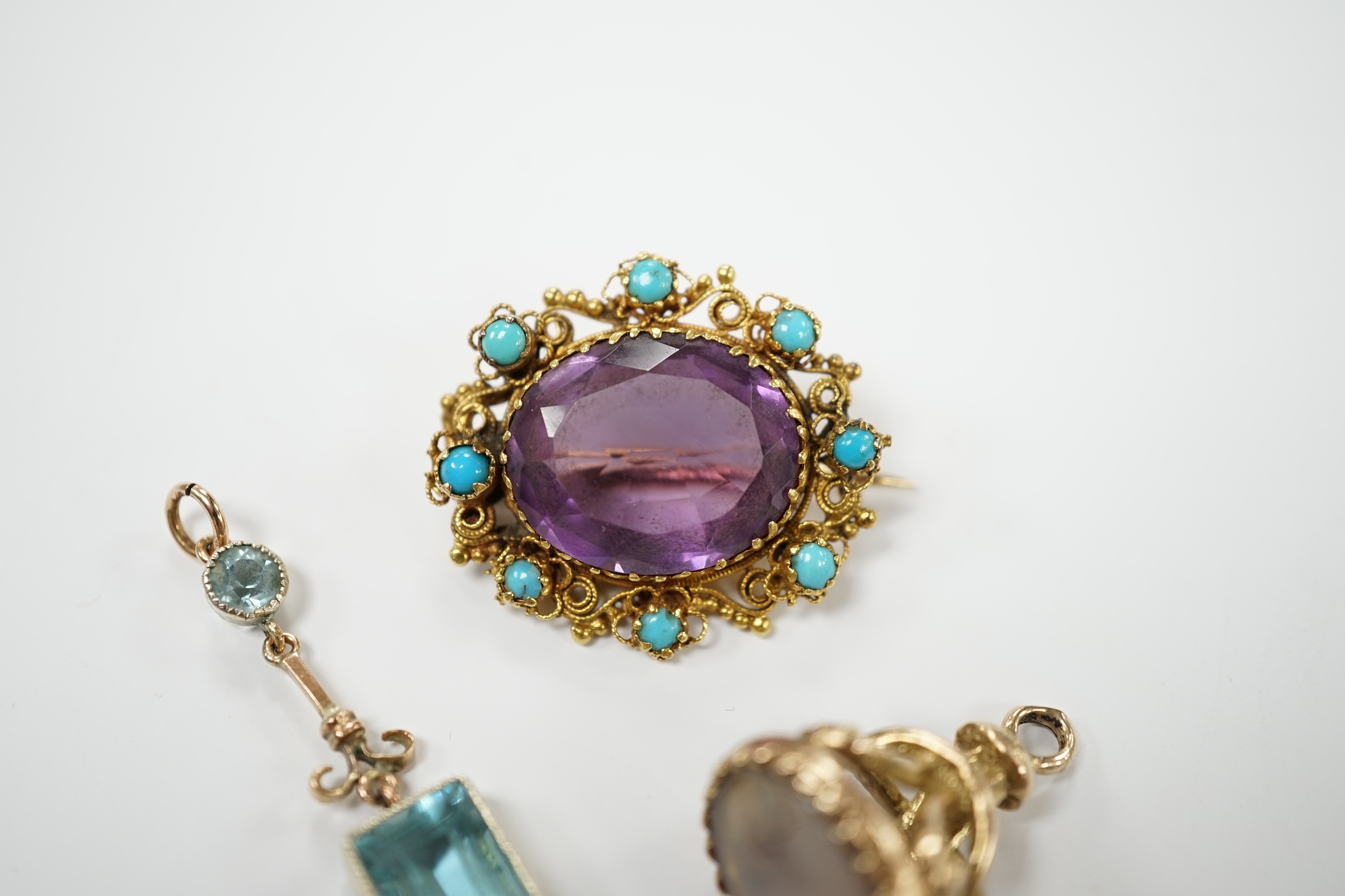 An early 20th century yellow metal, amethyst and turquoise set brooch, 25mm, a 9ct gold and white chalcedony set fob and a yellow metal and gem set drop pendant. Condition - poor to fair